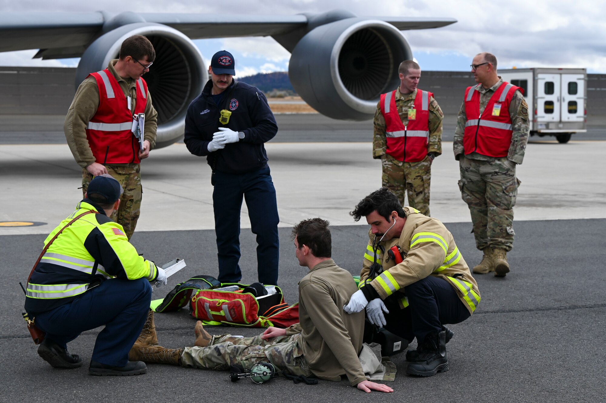 Firefighters listen to an Airman's breathing.