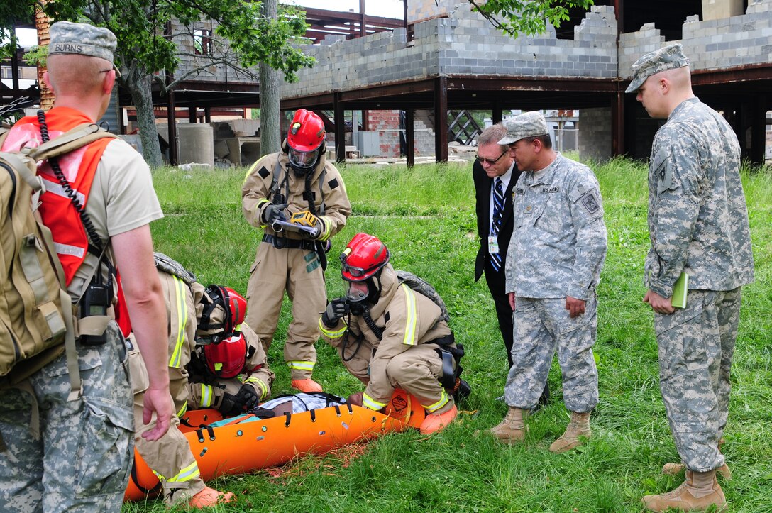 Maj. Pirom Srinual, Joint Collective Training Branch, National Guard Bureau, Maj. Paul A. Best, J39-Combatting Weapons Of Mass Destruction, National Guard Bureau and Mark Honeycutt, National Guard Bureau, observe Kentucky National Guardsmen transport a casualty during a training exercise May 23 at Muscatatuck Urban Training Center, Butlerville, Ind. The guardsmen are assigned to the Kentucky Chemical Radiological Nuclear High-Yield Explosives Enhanced Response Force Package which validated its mission May 24 at Muscatatuck Urban Training Center.