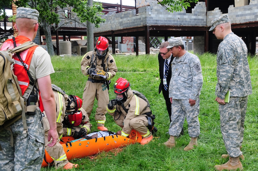 Maj. Pirom Srinual, Joint Collective Training Branch, National Guard Bureau, Maj. Paul A. Best, J39-Combatting Weapons Of Mass Destruction, National Guard Bureau and Mark Honeycutt, National Guard Bureau, observe Kentucky National Guardsmen transport a casualty during a training exercise May 23 at Muscatatuck Urban Training Center, Butlerville, Ind. The guardsmen are assigned to the Kentucky Chemical Radiological Nuclear High-Yield Explosives Enhanced Response Force Package which validated its mission May 24 at Muscatatuck Urban Training Center.