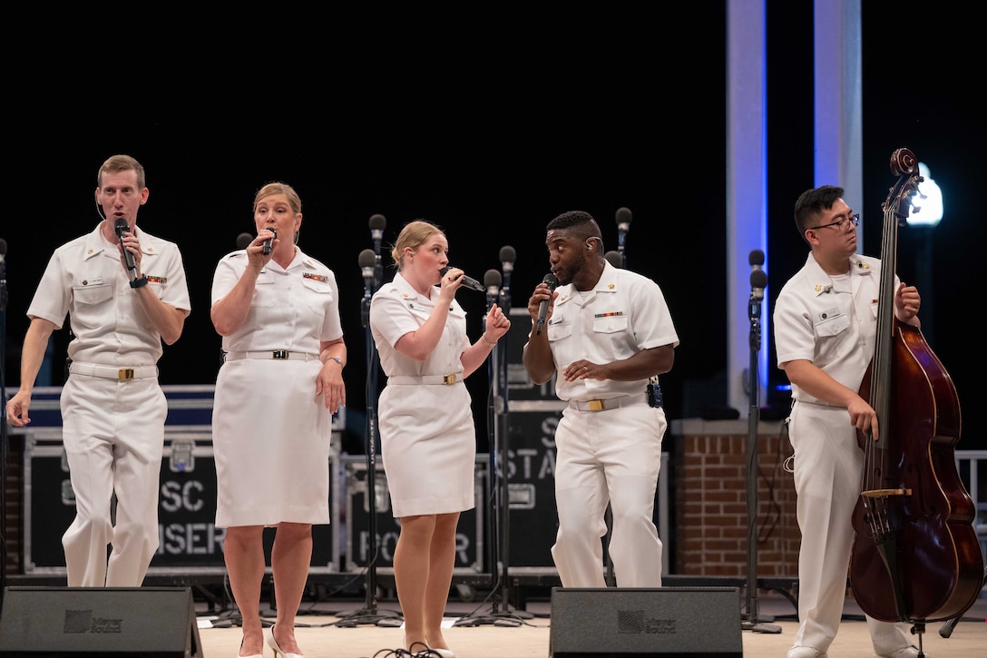 Four Navy singers and a upright bass player perform on stage.