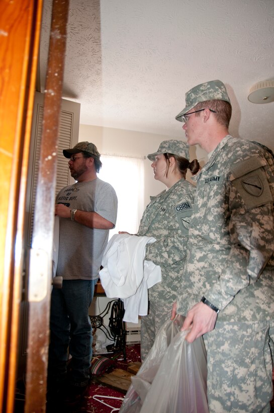 Kentucky National Guardsmen Pfc. Mary Lewis and Pfc. Kyle Gray, 301st Chemical Company, assist West Liberty, Ky., resident Daniel Leach gather clothing for victims of the tornado. Leach's apartment was destroyed during the tornado but clothing that belonged to his deceased mother was left untouched by the rain, wind and debris. "Maybe they can use it," he said. "Mom would've wanted that."