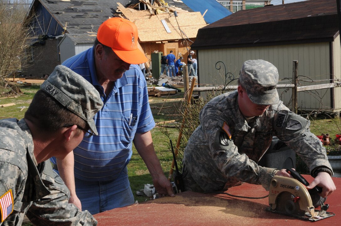 Kentucky National Guard Sgt. Sean Durban cuts a piece of plywood for retired Air Force veteran Thomas Coder, a West Liberty, Ky., resident, March 7. Durban and Pfc. Kyle Gray, both of the Morehead Ky.-based 301st Chemical Company, spent most of the day assisting residents with moving personal items, boarding up homes and passing out supplies following the March 2 tornado that devastated most of the Eastern Kentucky community.