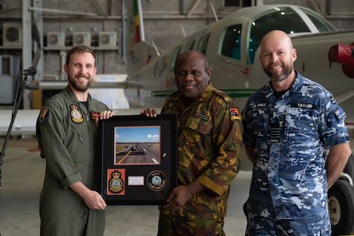 Royal Australian Air Force personnel present a gift to Papua New Guinea Defence Force Lt. Col. Douglas Vavar (middle), Air Wing commanding officer, at the closing ceremony for Pacific Angel 24-1 at Port Moresby, Papua New Guinea, Aug. 30, 2024. Pacific Angel 24-1 is a four-day search and rescue focused field training exercise and subject matter expert exchange. During the exercise Papua New Guinea Defence Force personnel received training and exchange knowledge with U.S. Air Force and Royal Australian Air Force experts on areas such as aircraft maintenance, adverse terrain survival and swift water personnel recovery. (U.S. Air Force photo by Airman 1st Class Carson Jeney)