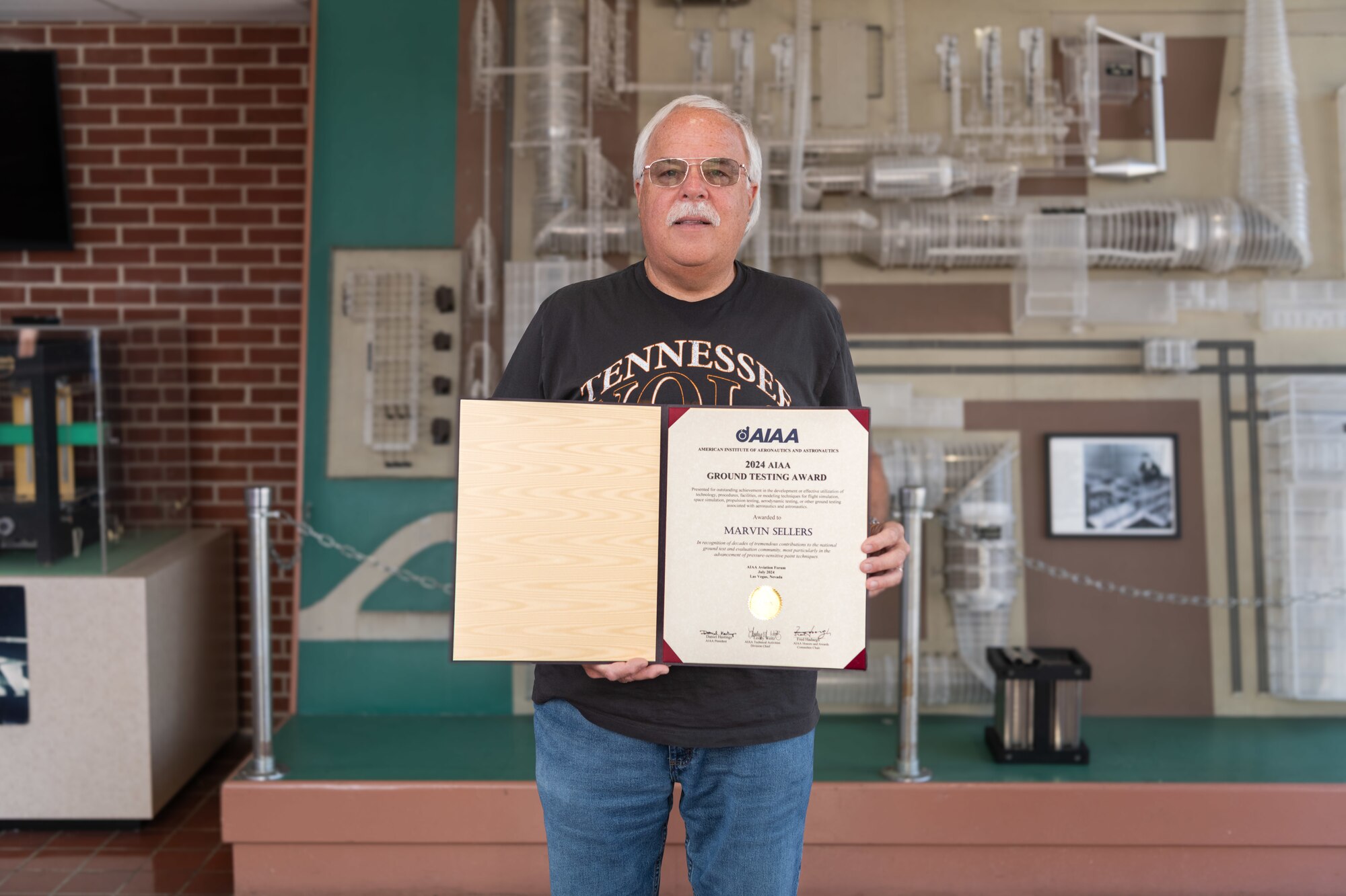 Marvin Sellers, a wind tunnel subject matter expert at Arnold Air Force Base, Tenn., headquarters of Arnold Engineering Development Complex, displays the certificate he received upon winning the 2024 American Institute of Aeronautics and Astronautics Ground Testing Award while in the lobby of the Propulsion Wind Tunnel facility at Arnold AFB, Aug. 20, 2024. His award citation states that Sellers was recognized for contributions to the national ground test and evaluation community, most particularly in the advancement of pressure-sensitive paint techniques. Sellers has led the development of PSP techniques at Arnold AFB since 1991. (U.S. Air Force photo by Keith Thornburgh)