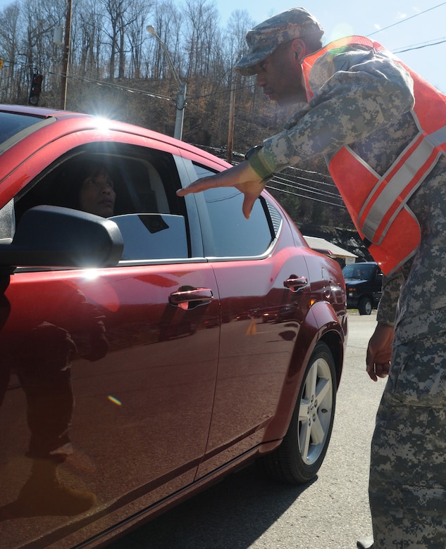 U.S. Army Pfc. Dominique Smallwood, a Chemical, Biological, Radiological and Nuclear specialist with the 299th Chemical Company, out of Maysville, Ky., helps direct traffic in the aftermath of the tornado and series of severe storms that destroyed most of West Liberty, Ky.