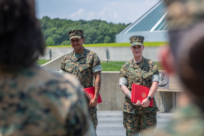 U.S. Marine Corps Cpl. Brandon Gillrivera, a motor vehicle operator at Officer Candidates School, left, and Sgt. Haley G. Gillrivera, a motor vehicle operator at The Basic School, listen to family and friends after their reenlistment ceremony at the National Museum of the Marine Corps, Triangle, Virginia, Aug. 1, 2024. The Gillriveras are a dual-military couple who decided to reenlist together, continue to develop their individual careers, and utilize the benefits the Marine Corps has to offer to their family. (U.S. Marine Corps photo by Lance Cpl. Anthony Ramsey)