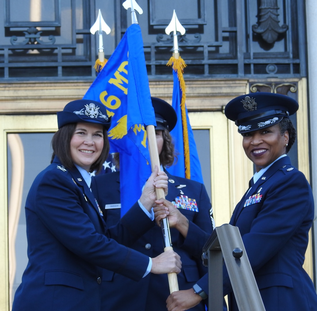 U.S. Air Force Col. Stacy Friesen (left), commander and director of the 316th Medical Group, Joint Base Andrews, passes the 316th Inpatient Squadron’s flag to U.S. Air Force Lt. Col. Falana Gideon, who assumed command of the new squadron on Aug. 23, 2024, making the squadron the first for the Air Force at Walter Reed National Military Medical Center.