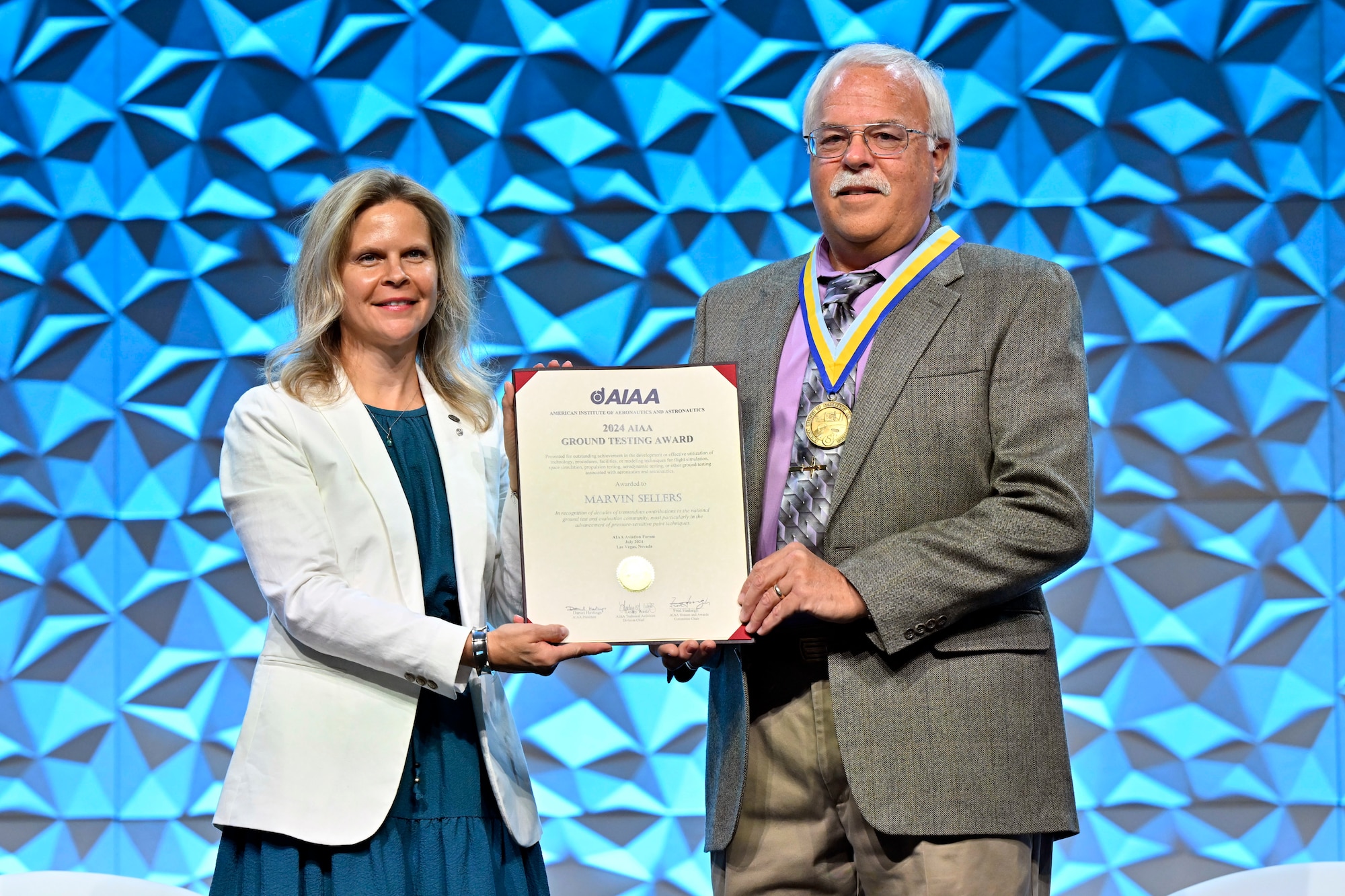 Marvin Sellers, a wind tunnel subject matter expert at Arnold Air Force Base, Tenn., headquarters of Arnold Engineering Development Complex, is joined by American Institute of Aeronautics and Astronautics Aerospace Sciences Group Director Martiqua Post on July 29, 2024, as he accepts the certificate recognizing him as the winner of the 2024 American Institute of Aeronautics and Astronautics Ground Testing Award during the AIAA AVIATION Forum, held July 29 to Aug. 2 in Las Vegas, Nevada. His award citation states that Sellers was recognized for contributions to the national ground test and evaluation community, most particularly in the advancement of pressure-sensitive paint techniques. Sellers has led the development of PSP techniques at Arnold AFB since 1991. (Courtesy photo)