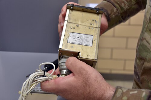 A man holds an aircraft component.