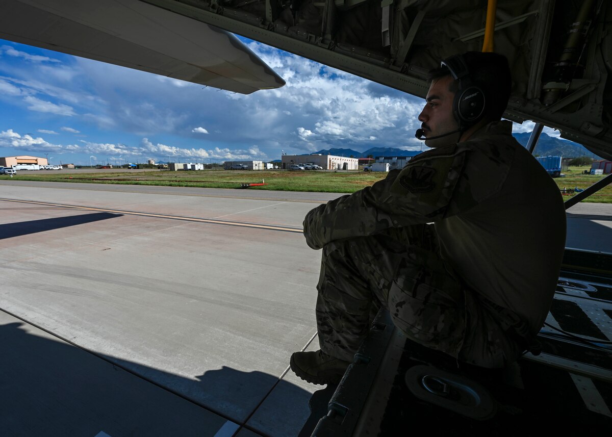 A man in a military uniform sits at the back of a plane
