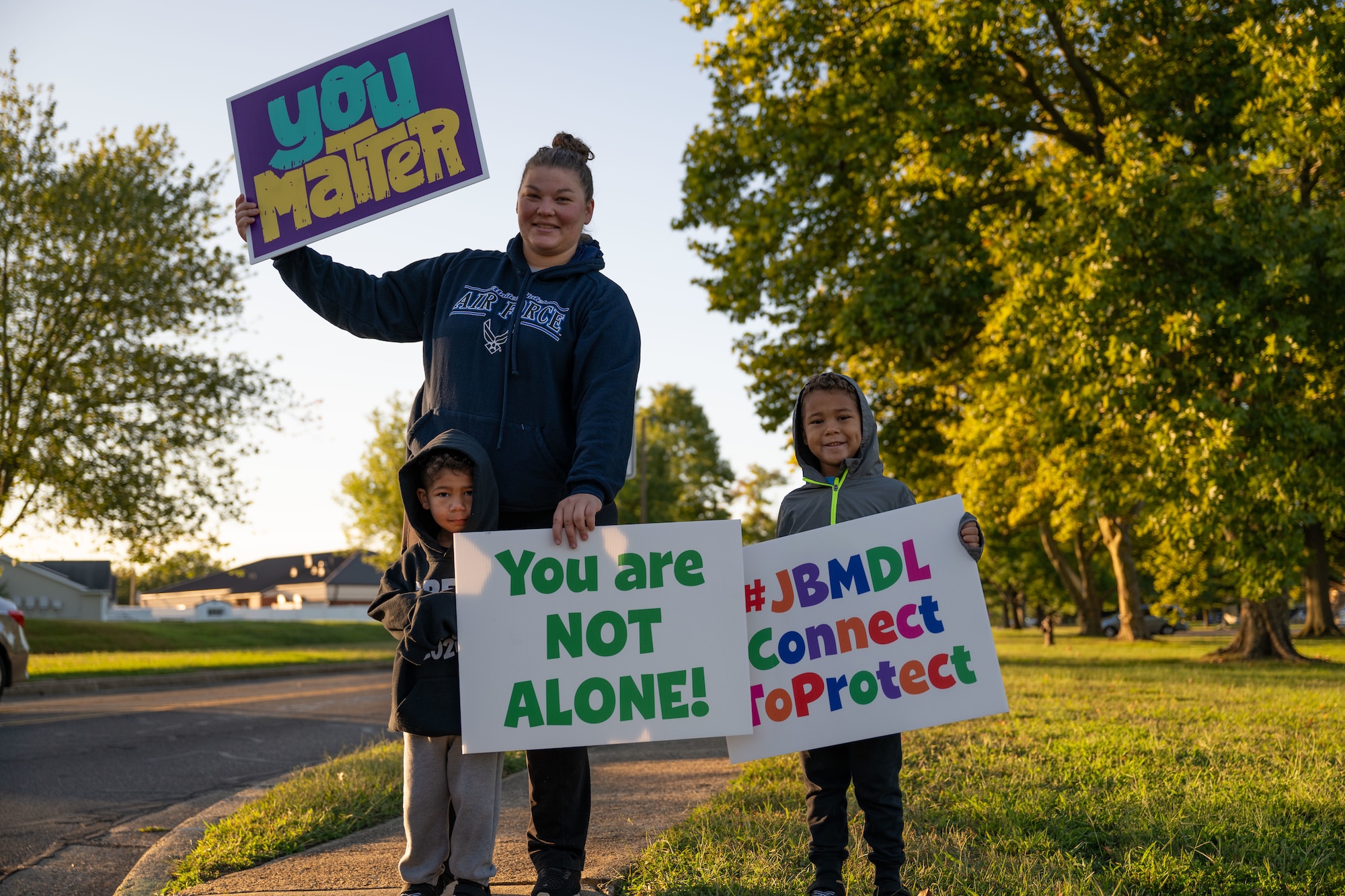 A volunteer and her children hold up encouraging signs during a National Suicide Prevention Awareness Month event at Joint Base McGuire-Dix-Lakehurst, N.J., Sept. 3, 2024. The month of September is the National Suicide Prevention Awareness Month where many organizations make a concerted effort to destigmatize the mental health struggles that many may face and take the opportunity to educate the public on recognizing signs someone is need of support as well as the avenues to receive support. (U.S. Air Force photo by Staff Sgt. Monica Roybal)