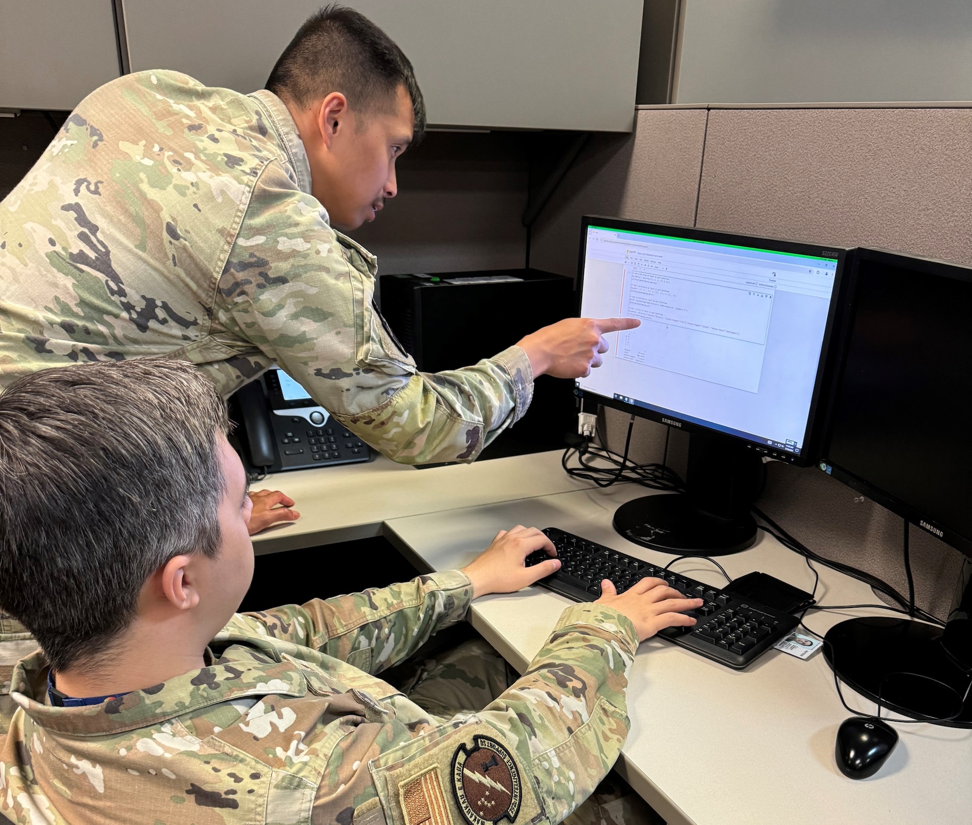 Two Airmen look at computer screen.