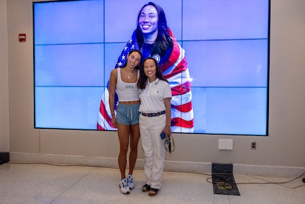 USA Olympic swimmer Torri Huske, poses with mother, Carderock IT Specialist Ying Huske, in front of a photo of Torri at the 2024 Paris Olympics.