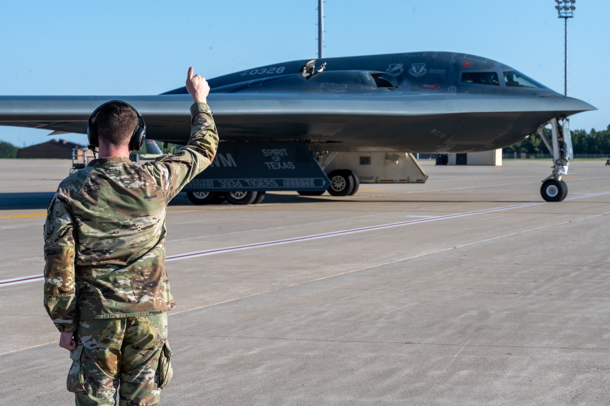 A U.S. Air Force Airman gives a B-2 Spirit stealth bomber the "thumbs up" signal on the flight line at Whiteman Air Force Base