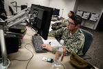 Soldier works behind keyboard.