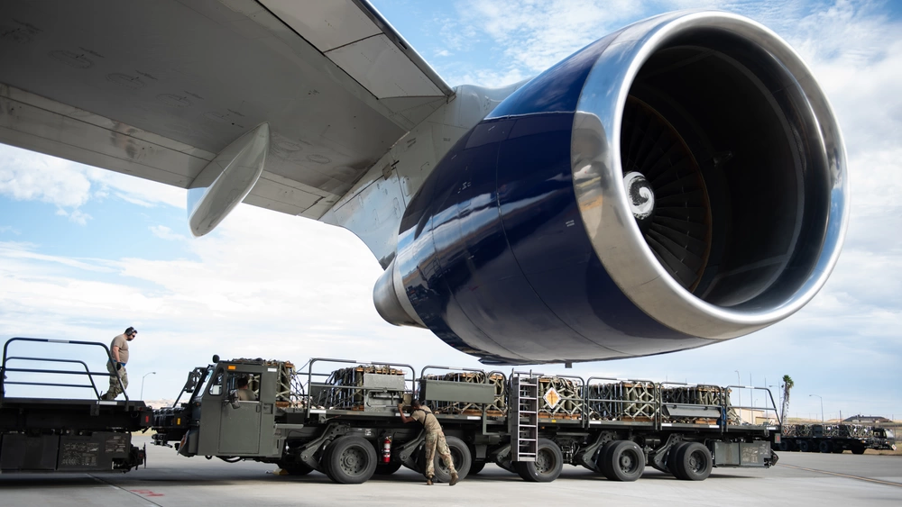 U.S. Airmen assigned to the 60th Aerial Port Squadron load pallets of ammunition, shown in the background, onto a contracted aircraft, shown in the foreground, bound for Ukraine during a security assistance mission at Travis Air Force Base, California, June 25, 2024.