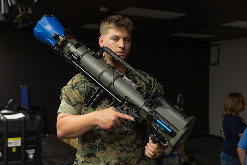 A Marine holds a large weapon.