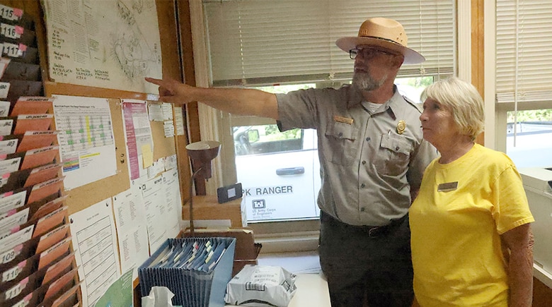 Man pointing at a board with a woman looking on.