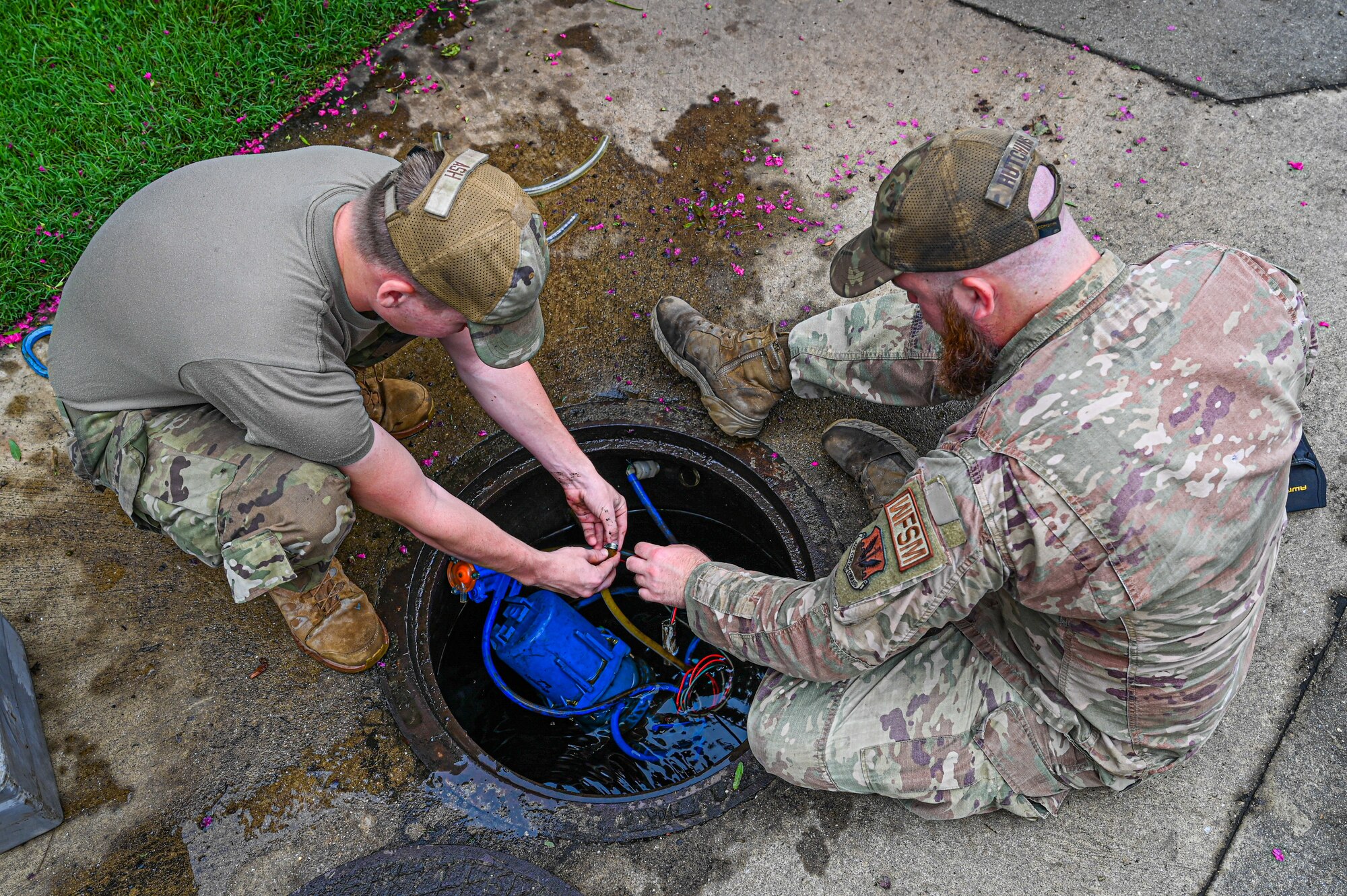 Photos from above of two Airmen working together to fix an issue within a manhole.