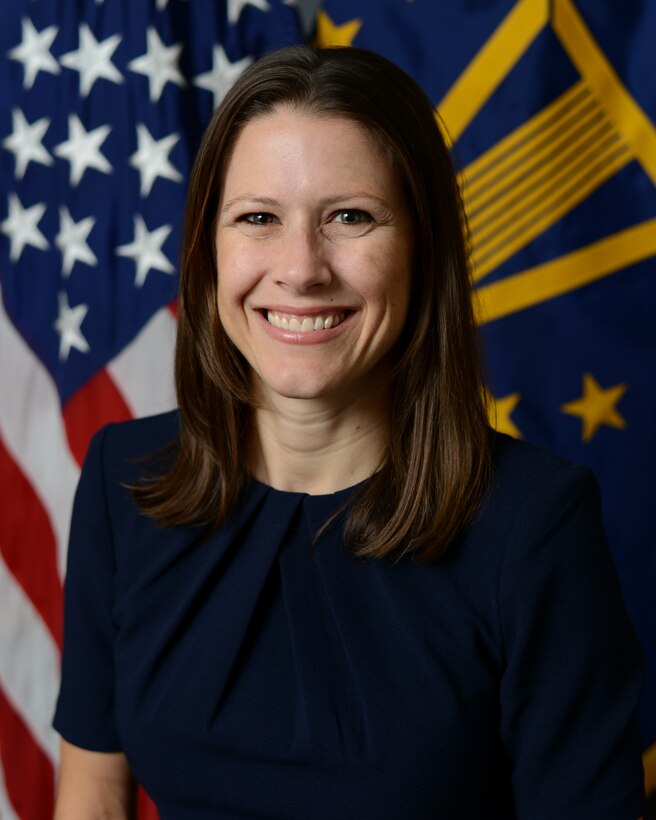 A woman poses in front of two flags.