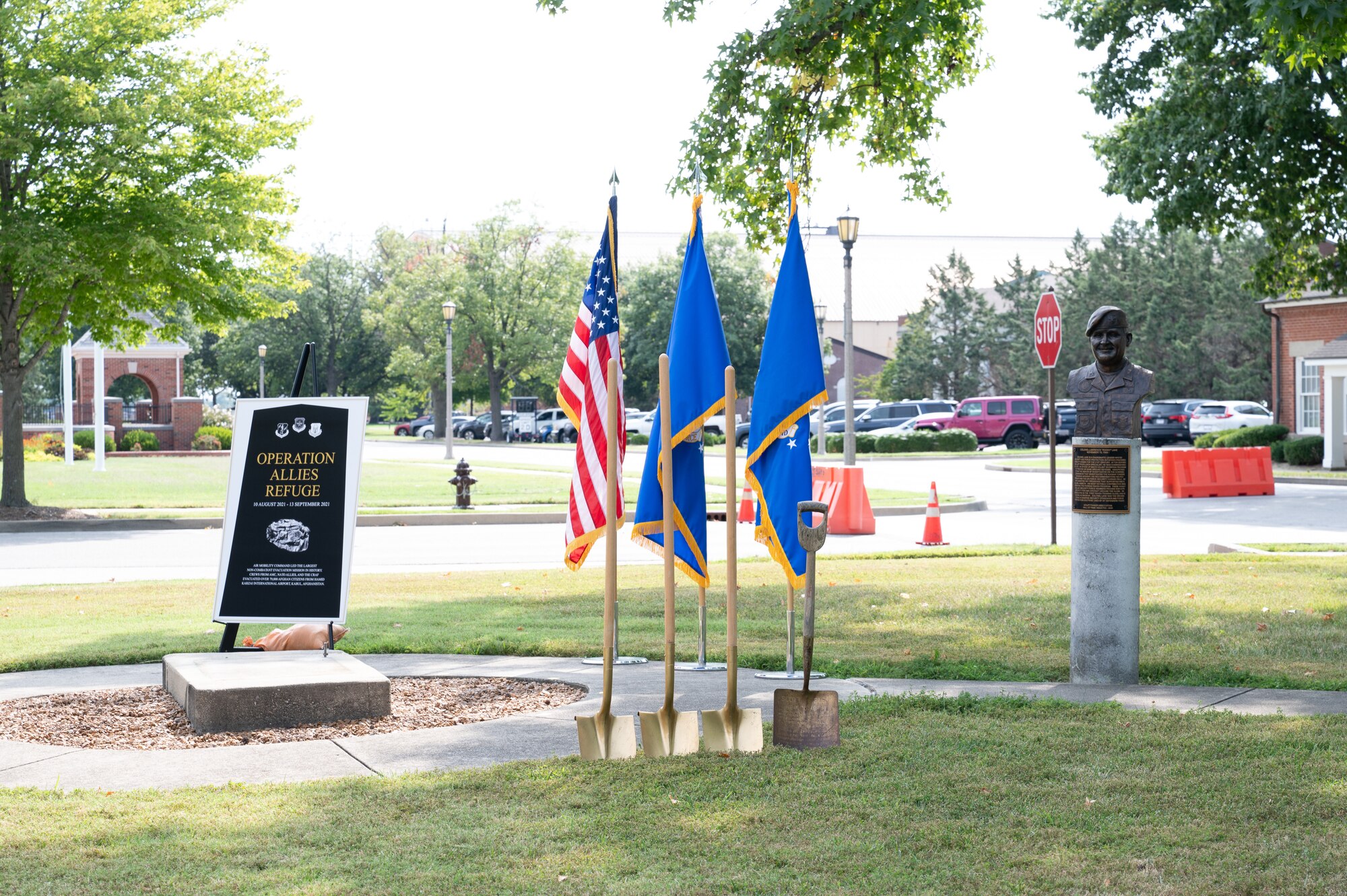 Ceremonial shovels stand at attention in front of three flags.