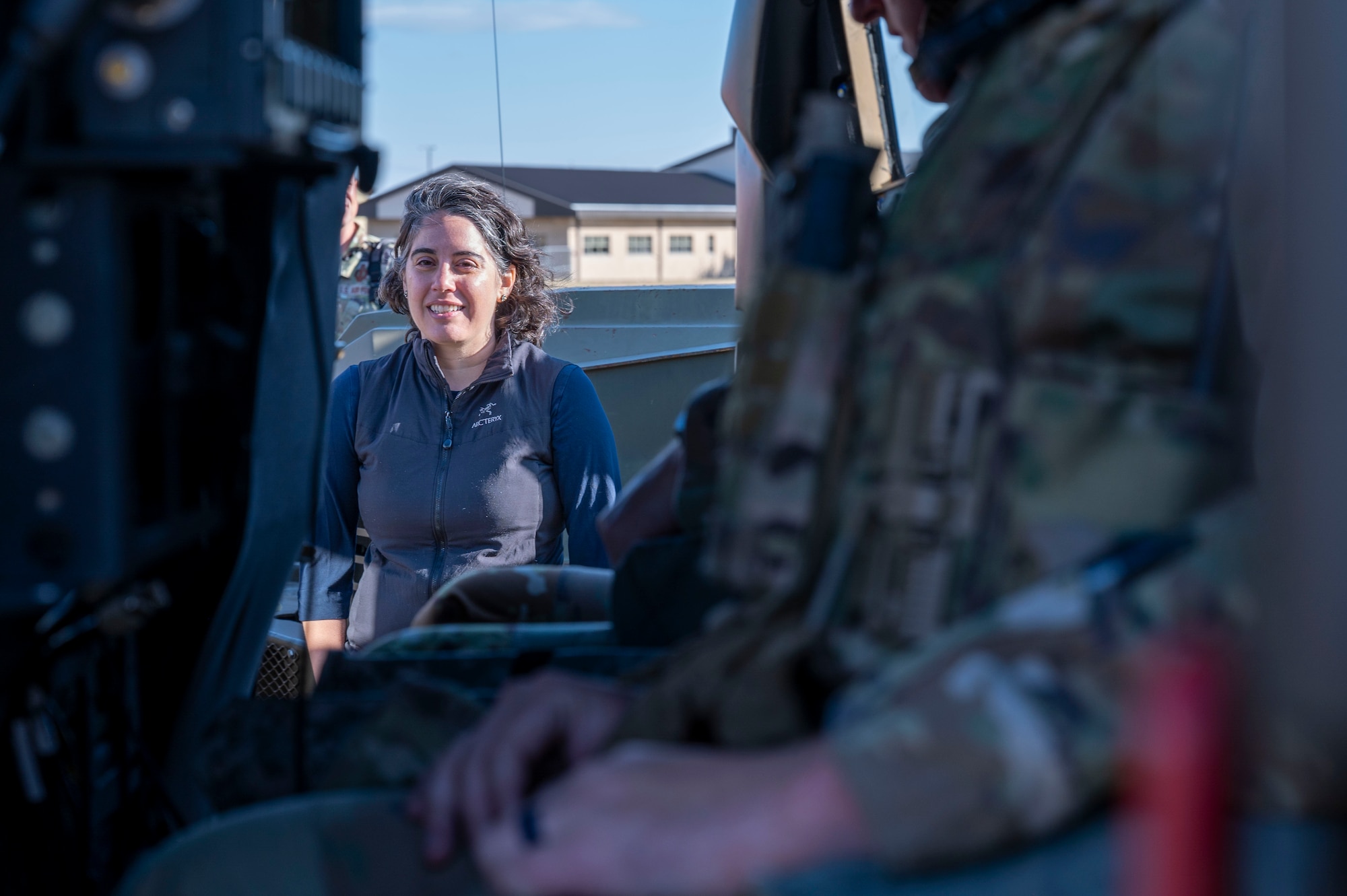 A woman watching as Airmen demonstrate how they use a military vehicle