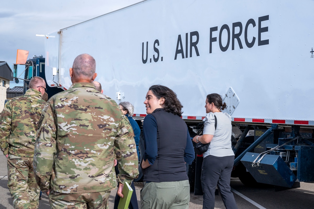 A group of people walk in front of a truck that says U.S. Air Force.