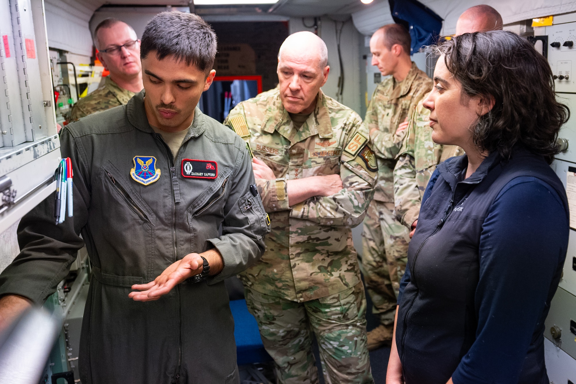 A missileer gestures toward something he is speaking about to a group of paople.