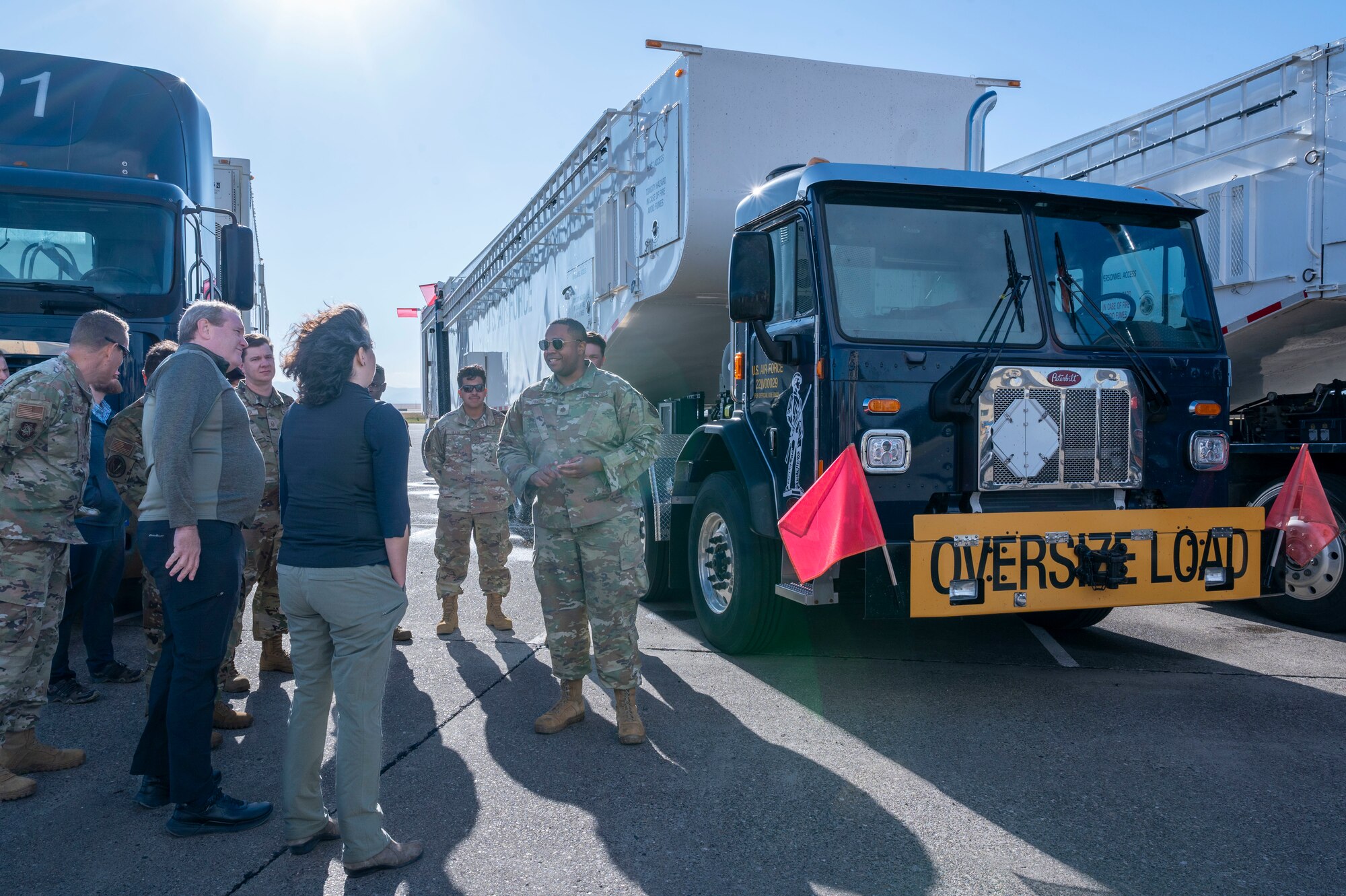 An Airman talks to a group of people while standing in front of a missile maintenance vehicle.