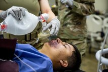 U.S. Air Force Airman 1st Class Andre Medina, an exercise casualty actor, receives simulated medical treatment during an Emergency Management exercise.