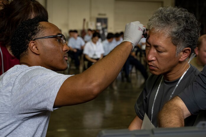 U.S. Air Force Senior Airman Niles Tilley, 35th Operational Medical Readiness Squadron public health technician, applies moulage makeup to a casualty actor during an Emergency Management exercise.