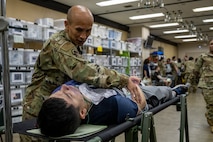 U.S. Air National Guard Maj. Hung Bui, 141st Medical Group nurse, simulates medical response for casualty actor U.S. Air Force Airman 1st Class Andre Medina, 35th Fighter Wing Public Affairs apprentice, during an Emergency Management exercise.