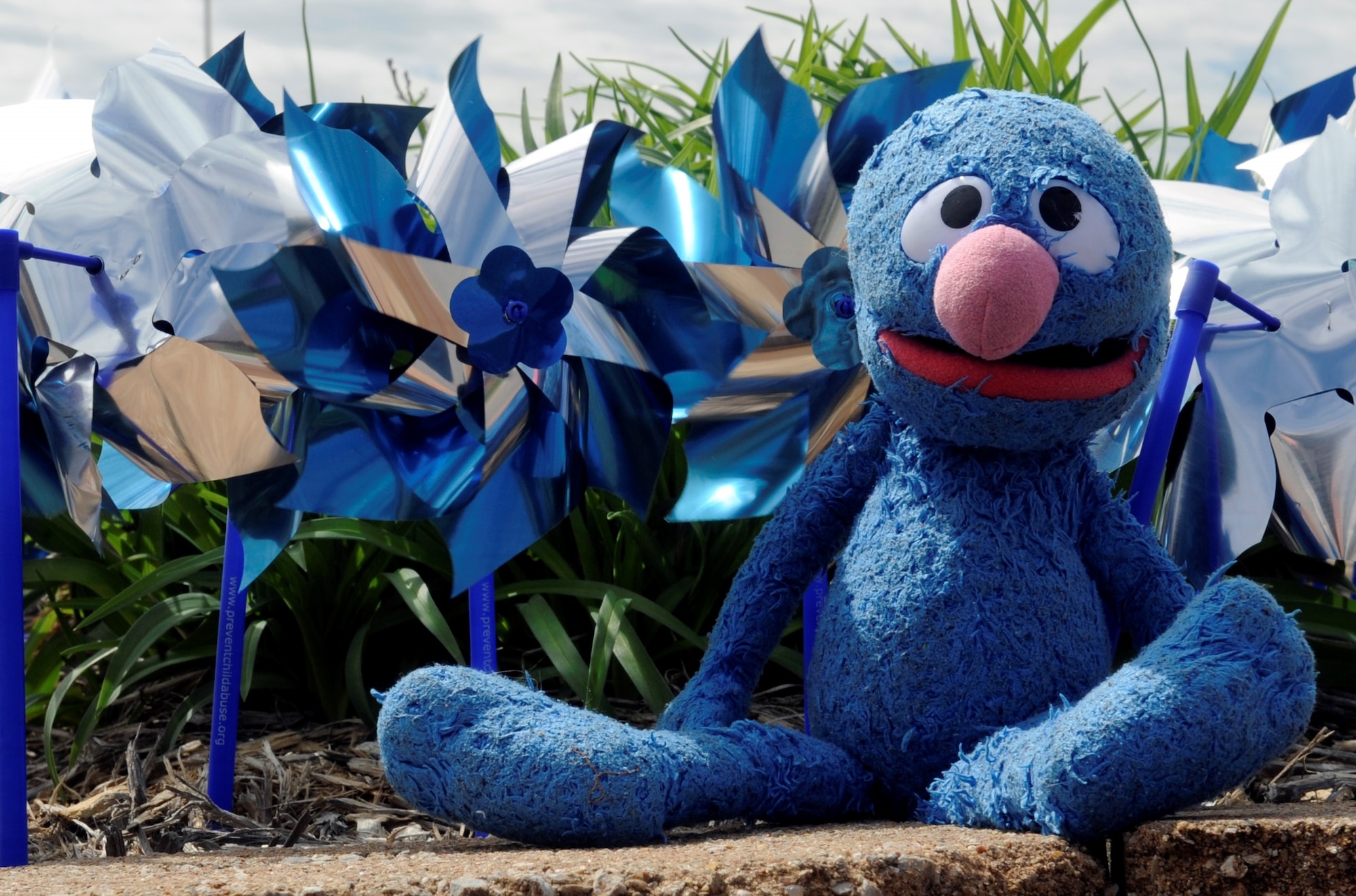 Grover, a Sesame Street character plush, sits alongside blue and silver pinwheels