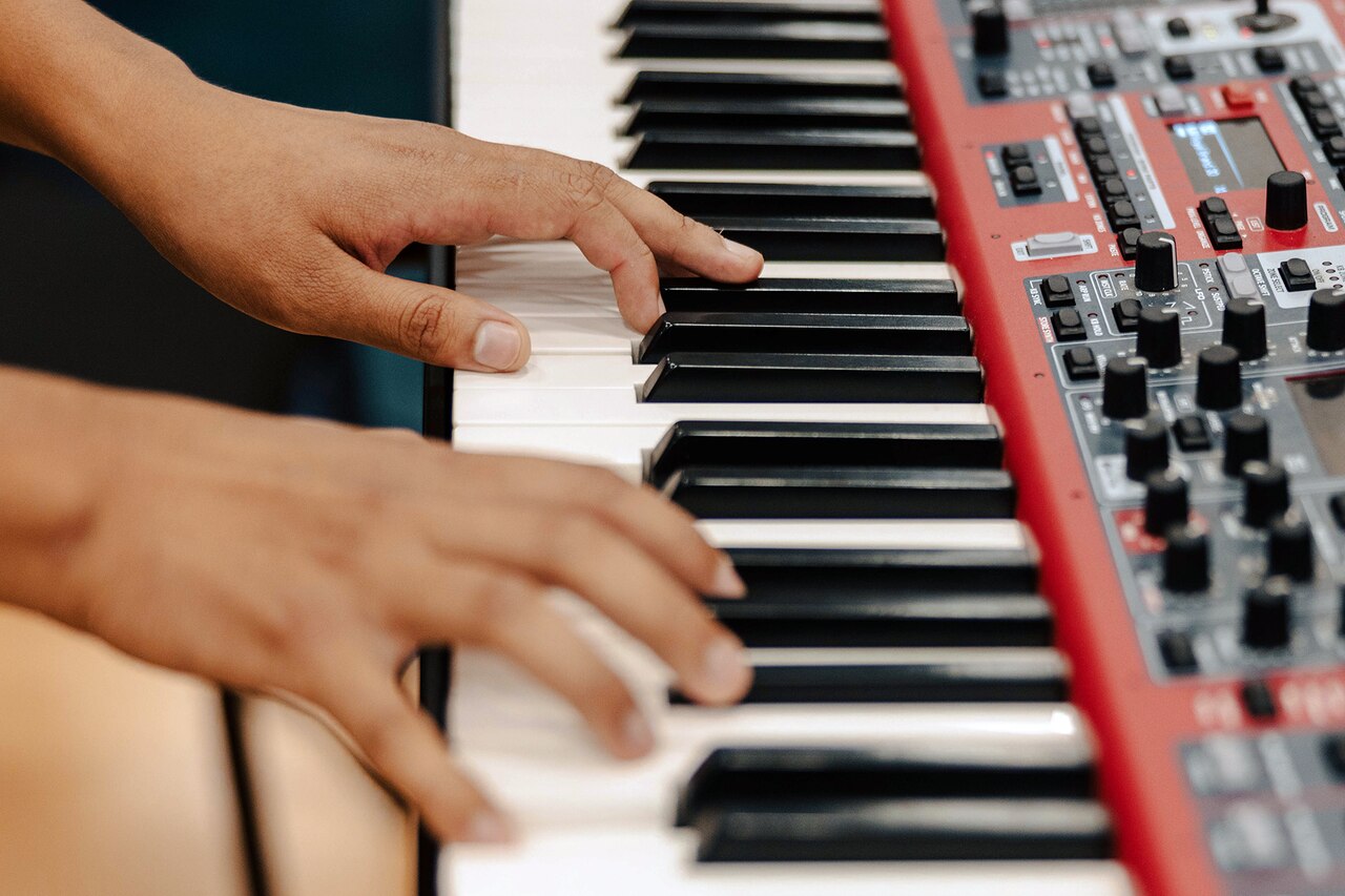Hands play on a keyboard instrument.