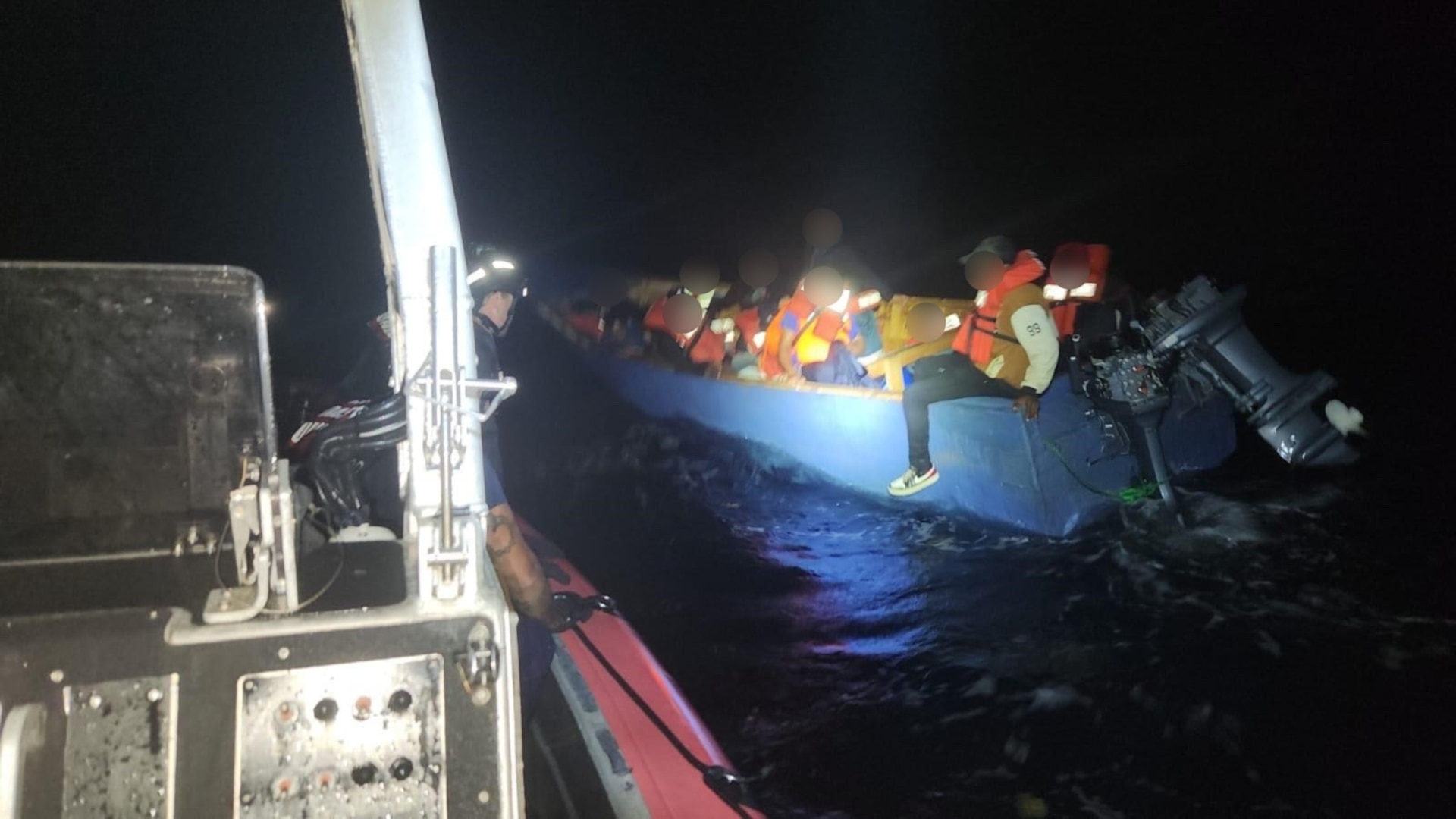 The crew of the Coast Guard Cutter Joseph Tezanos cutter boat assists the passengers of a disabled makeshift vessel taking on water in Atlantic Ocean waters northeast of Samana, Dominican Republic, Monday night.  The Joseph Tezanos crew provided life jackets and assisted with the transfer of all 20 migrants to the Dominican Republic Navy patrol boat Capella.  (U.S. Coast Guard photo)