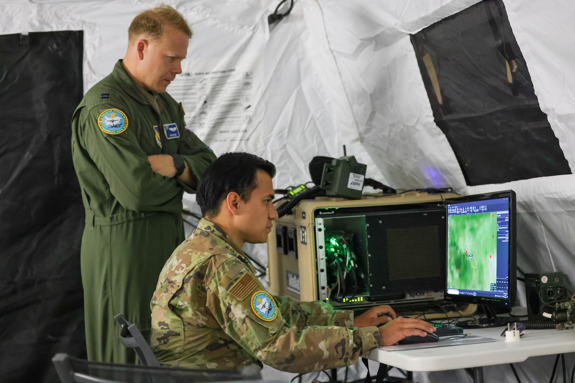 U.S. Air Force Capt. Zachary Palisch, 37th Airlift Squadron training flight commander, and U.S. Air Force Senior Airman Rene Gomez, 86th Communications Squadron expeditionary communications technician, inspect network connections for ground operations and operators in the sky during Thracian Summer 2024, August 20, 2024, in Plovdiv, Bulgaria.