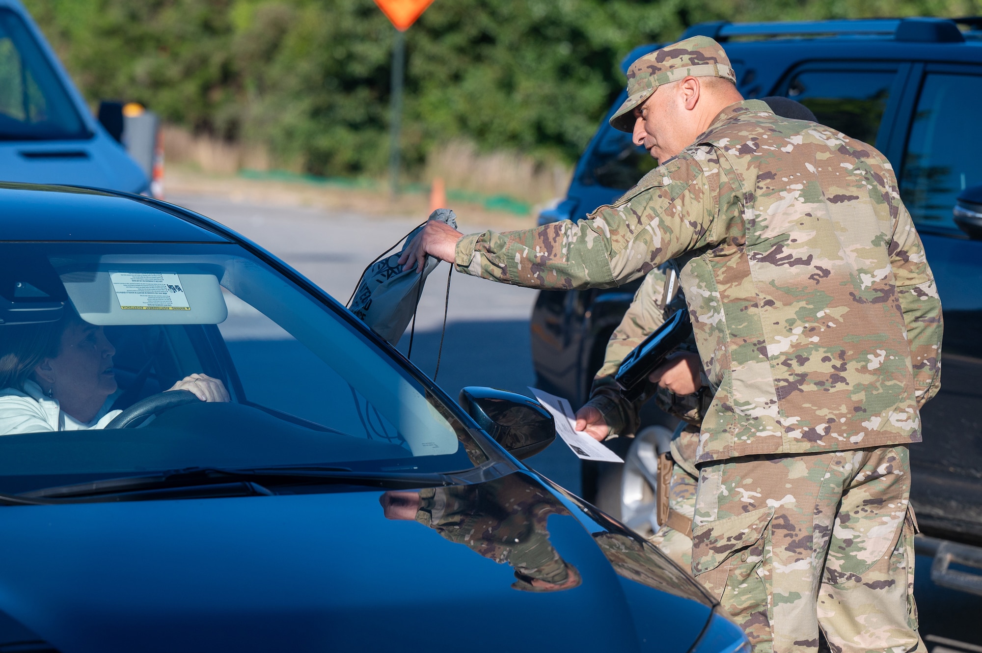 Image of person handing out items to someone in a car.