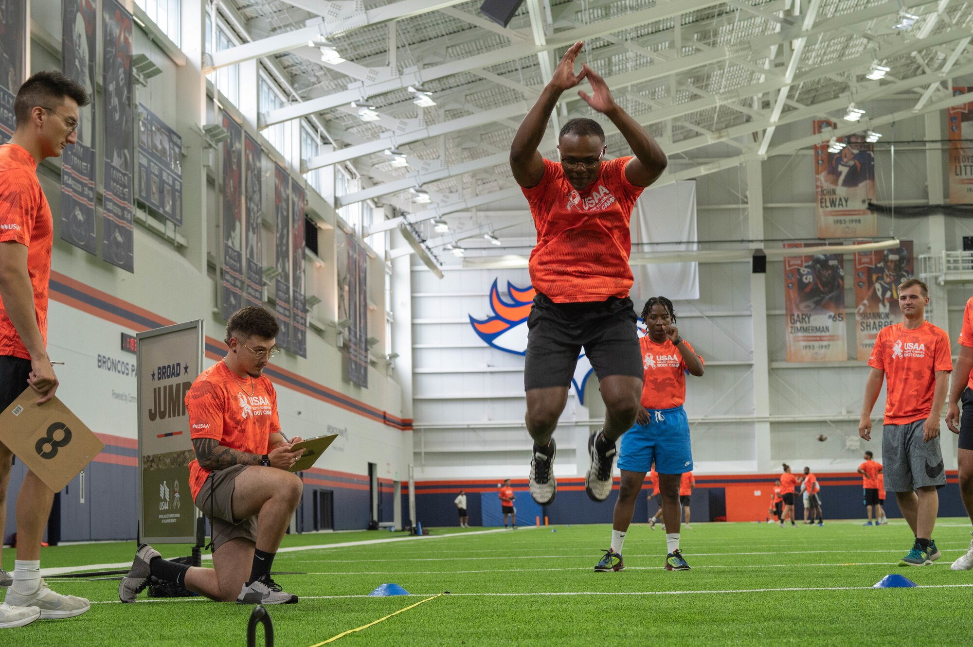 Service member is attempting the broad jump at the Denver Broncos training camp.