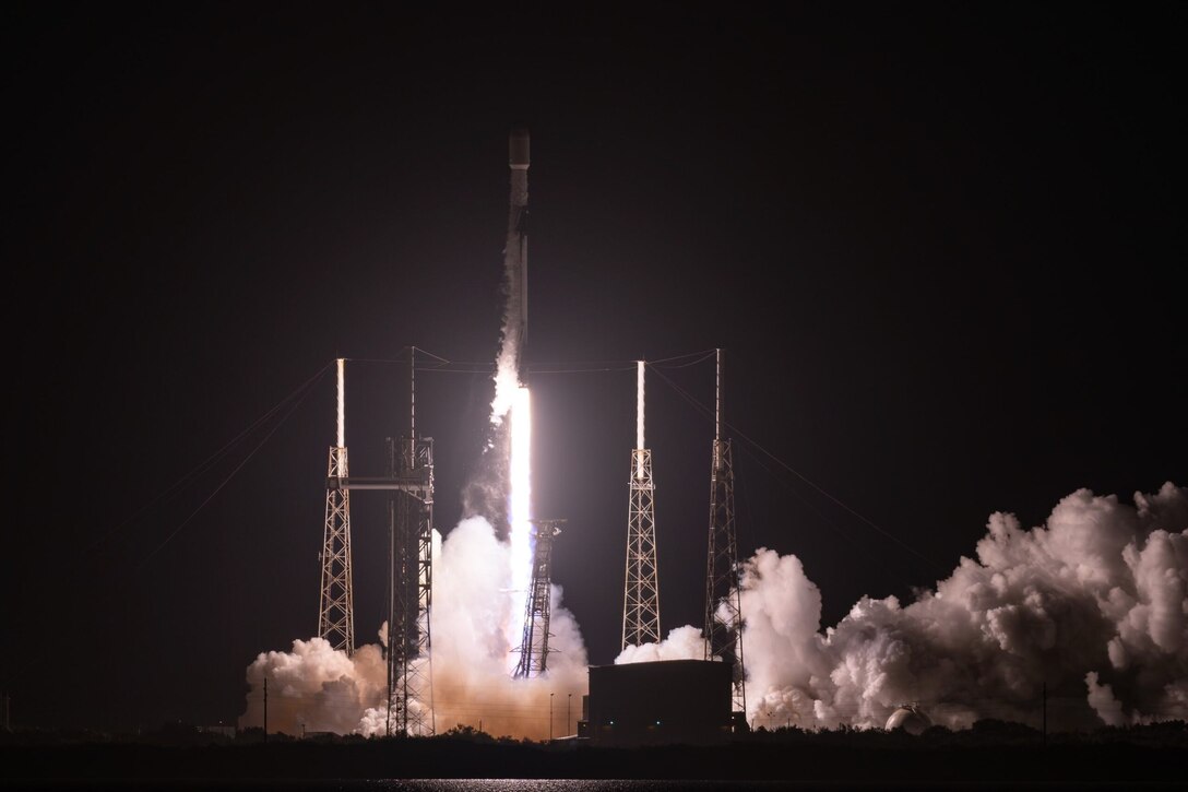 A rocket launches from its pad at night.