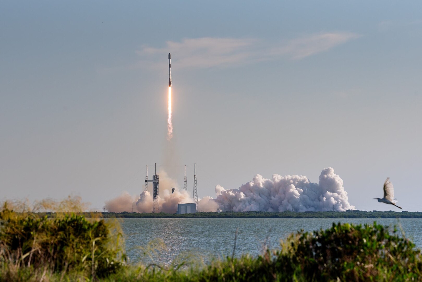 A rocket launches from its pad in the daytime.