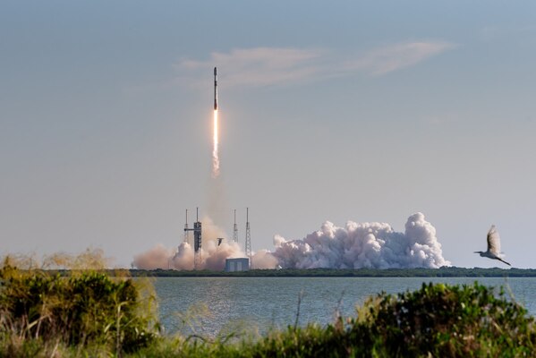 A rocket launches from its pad in the daytime.