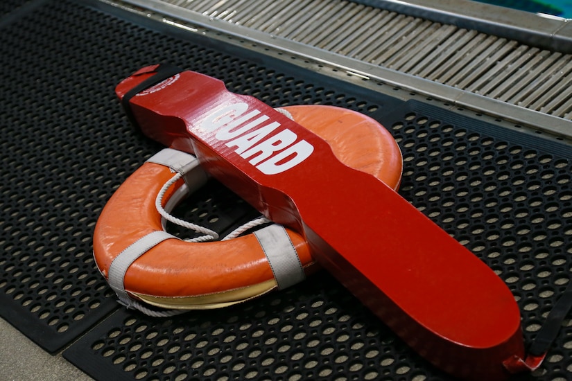 Lifeguard gear rests next to an indoor pool.