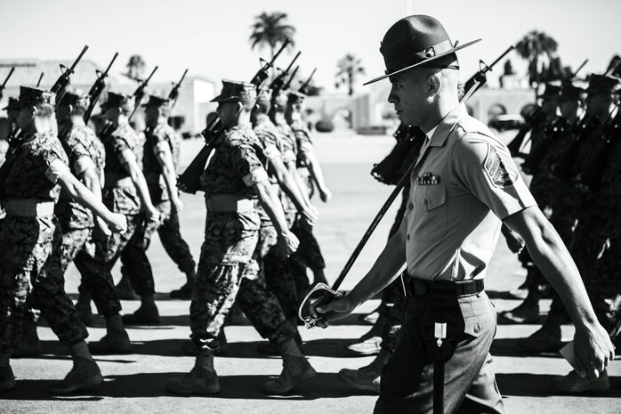 U.S. Marine Corps Staff Sgt. Aaron Ruiz, a senior drill instructor with Lima Company, 3rd Recruit Training Battalion, marches his platoon during a final drill evaluation at Marine Corps Recruit Depot San Diego, California, Aug. 24, 2024. During the final drill evaluation, the platoons are scored based on their uniforms, bearing, and movements, as well as the senior drill instructor’s cadence, sword control, and movement commands. (U.S. Marine Corps photo illustration by Sgt. Jesse K. Carter-Powell)