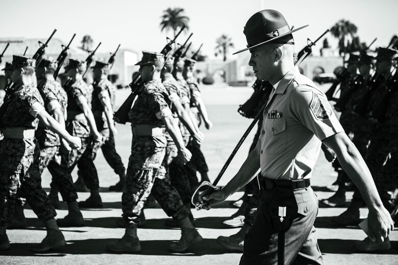 U.S. Marine Corps Staff Sgt. Aaron Ruiz, a senior drill instructor with Lima Company, 3rd Recruit Training Battalion, marches his platoon during a final drill evaluation at Marine Corps Recruit Depot San Diego, California, Aug. 24, 2024. During the final drill evaluation, the platoons are scored based on their uniforms, bearing, and movements, as well as the senior drill instructor’s cadence, sword control, and movement commands. (U.S. Marine Corps photo illustration by Sgt. Jesse K. Carter-Powell)