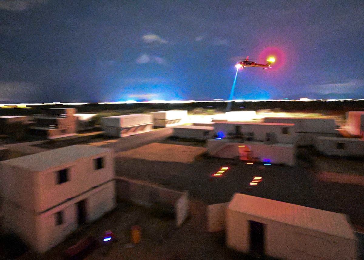 A helicopter flying over buildings at night
