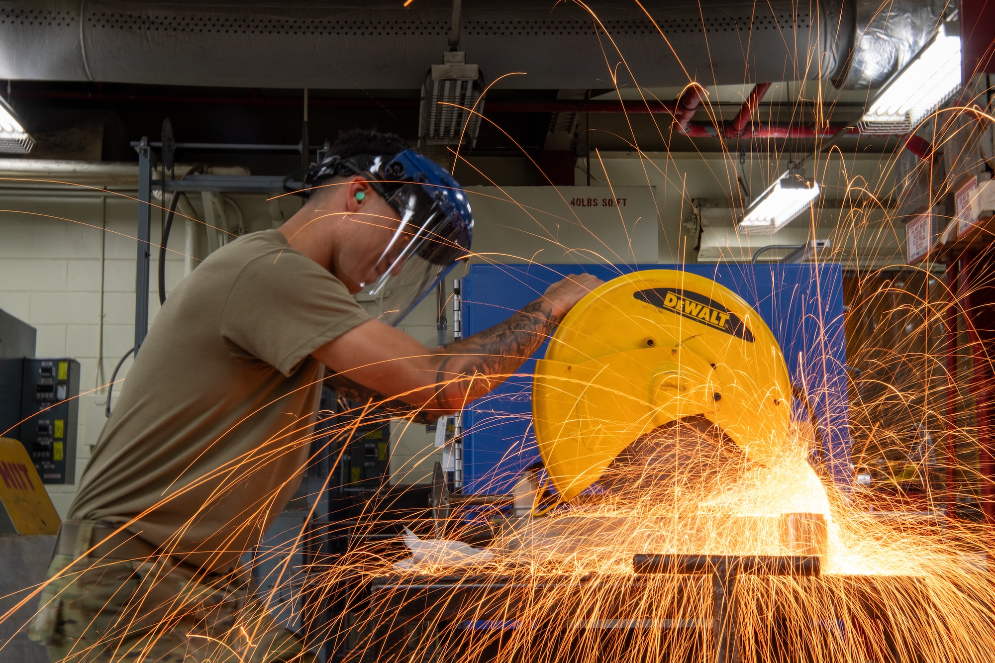 Airman using a sliding miter saw to cut a piece of metal