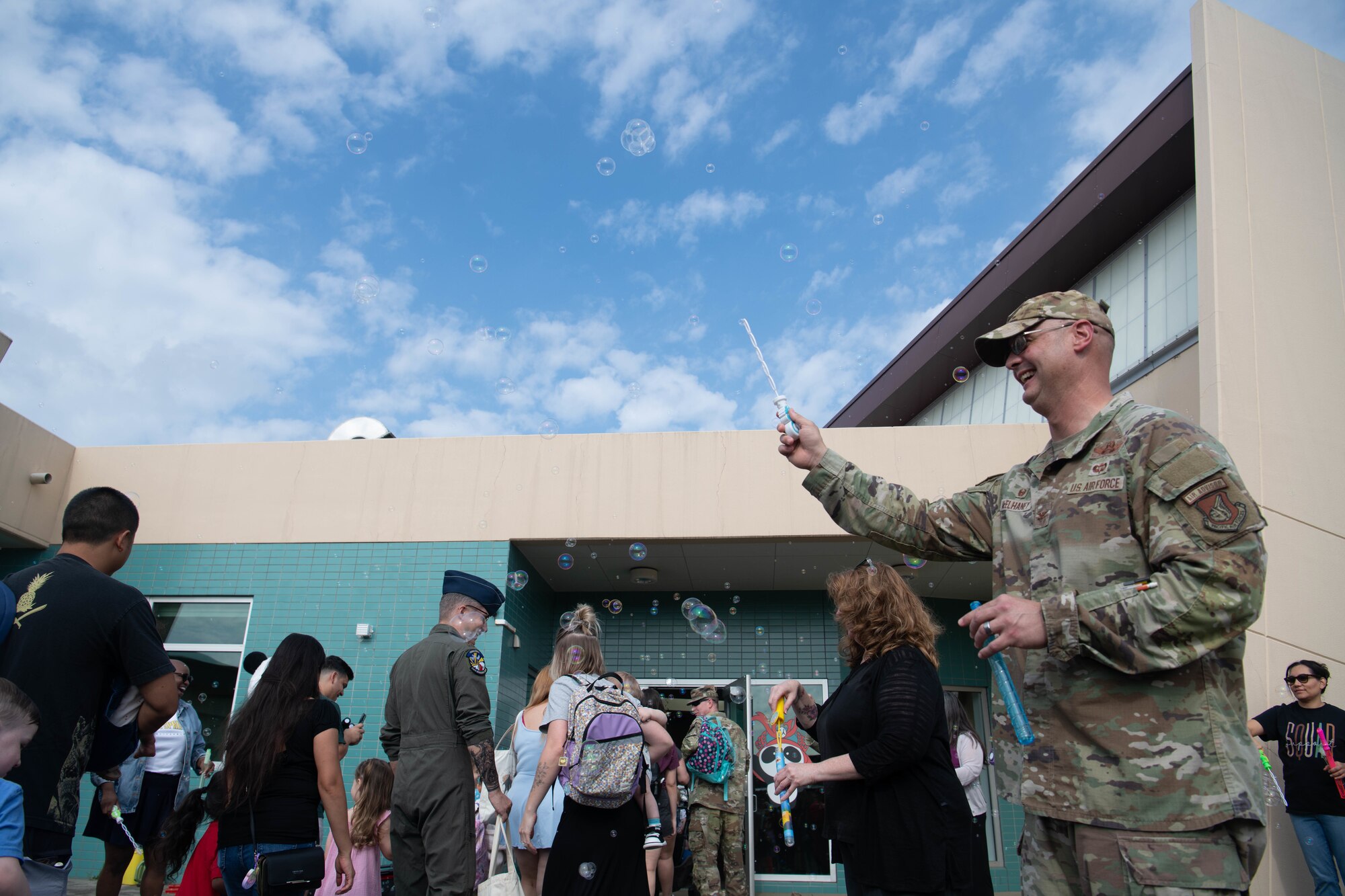 U.S. Air Force Col. Richard McElhaney, 374th Airlift Wing commander, blows bubbles as students enter Mendel Elementary School.