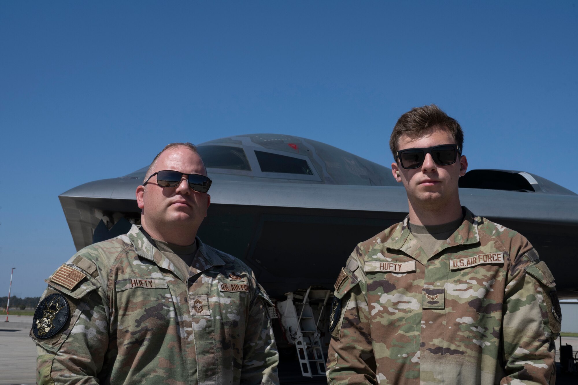 U.S. Air Force Chief Master Sgt. Adam Hufty, 110th Expeditionary Bomb Squadron senior enlisted leader, and Airman 1st Class Ashton Hufty, 110th EBS all source intelligence analyst, pose in front of a B-2 Spirit stealth bomber during their Bomber Task Force deployment at Royal Australian Air Force Base Amberley, Australia, Sept. 4, 2024. Adam is serving in the final years of his career while son, Ashton has just begun his Air Force career with just more than one year served. (U.S. Air Force photo by Tech. Sgt. Anthony Hetlage)