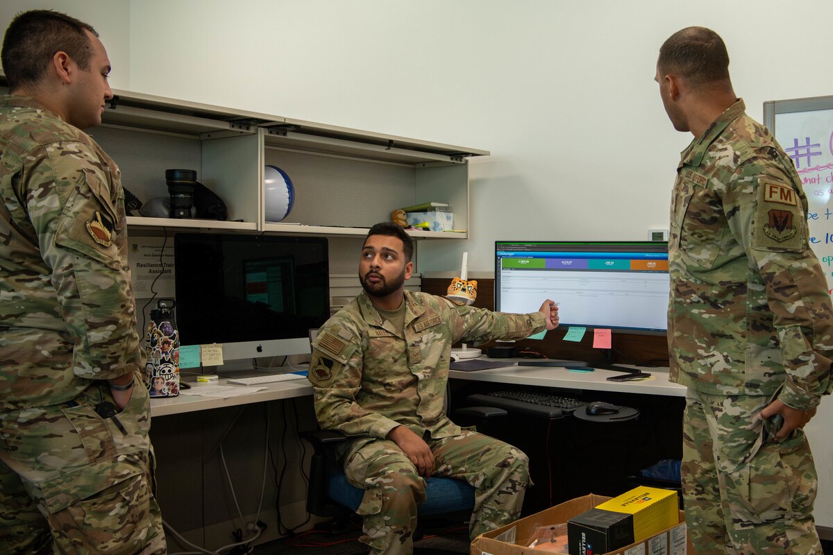Three Airmen discuss information shown on a computer.
