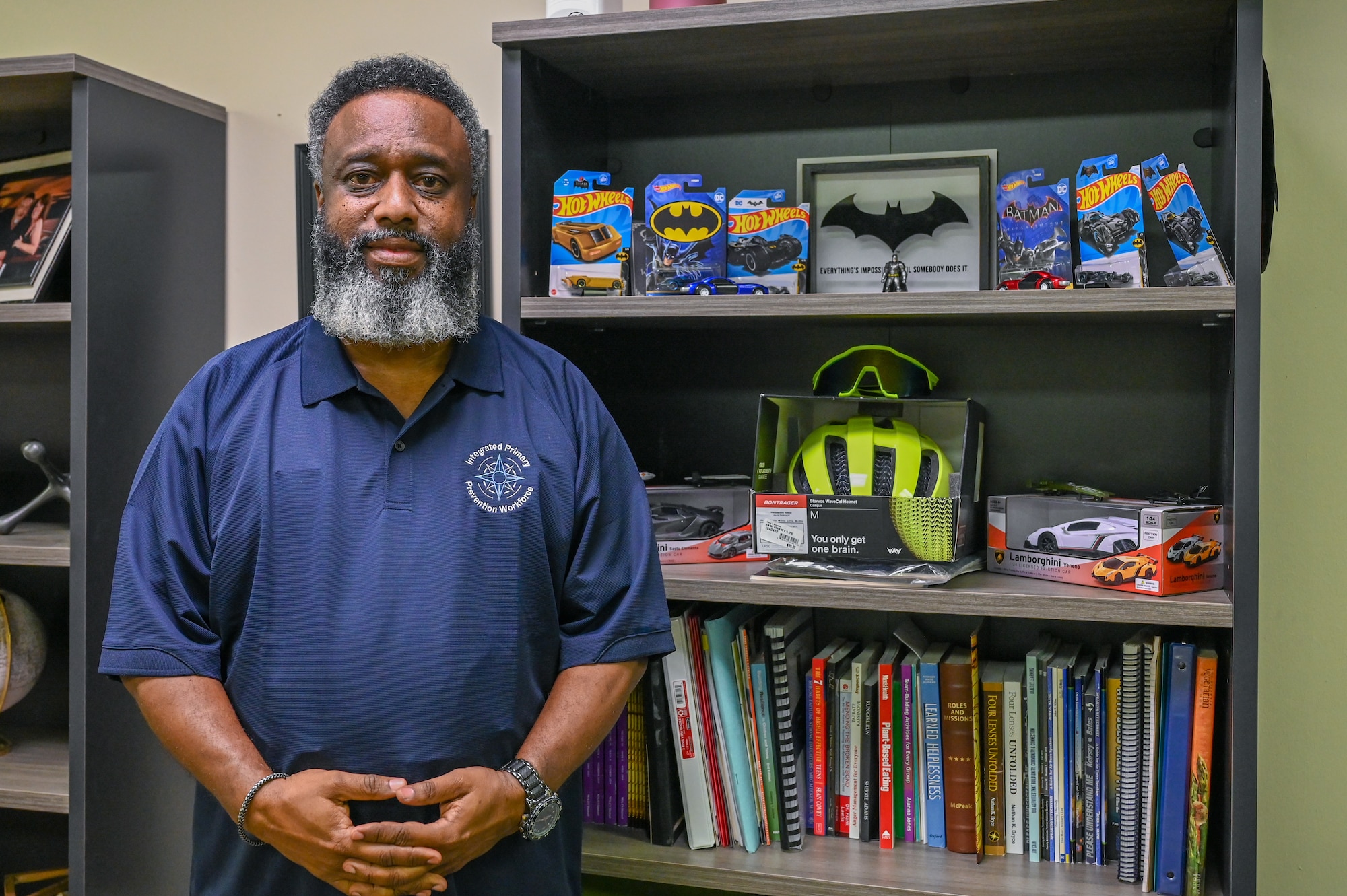 Wendell Browne, 97th Air Mobility Wing prevention specialist, poses with his Batman themed shelf in his office at Altus Air Force Base, Oklahoma, Aug. 21, 2024. Browne chose to decorate his office with Batman themed knick-knacks because of the superhero’s resilience. (U.S. Air Force photo by Senior Airman Kari Degraffenreed)